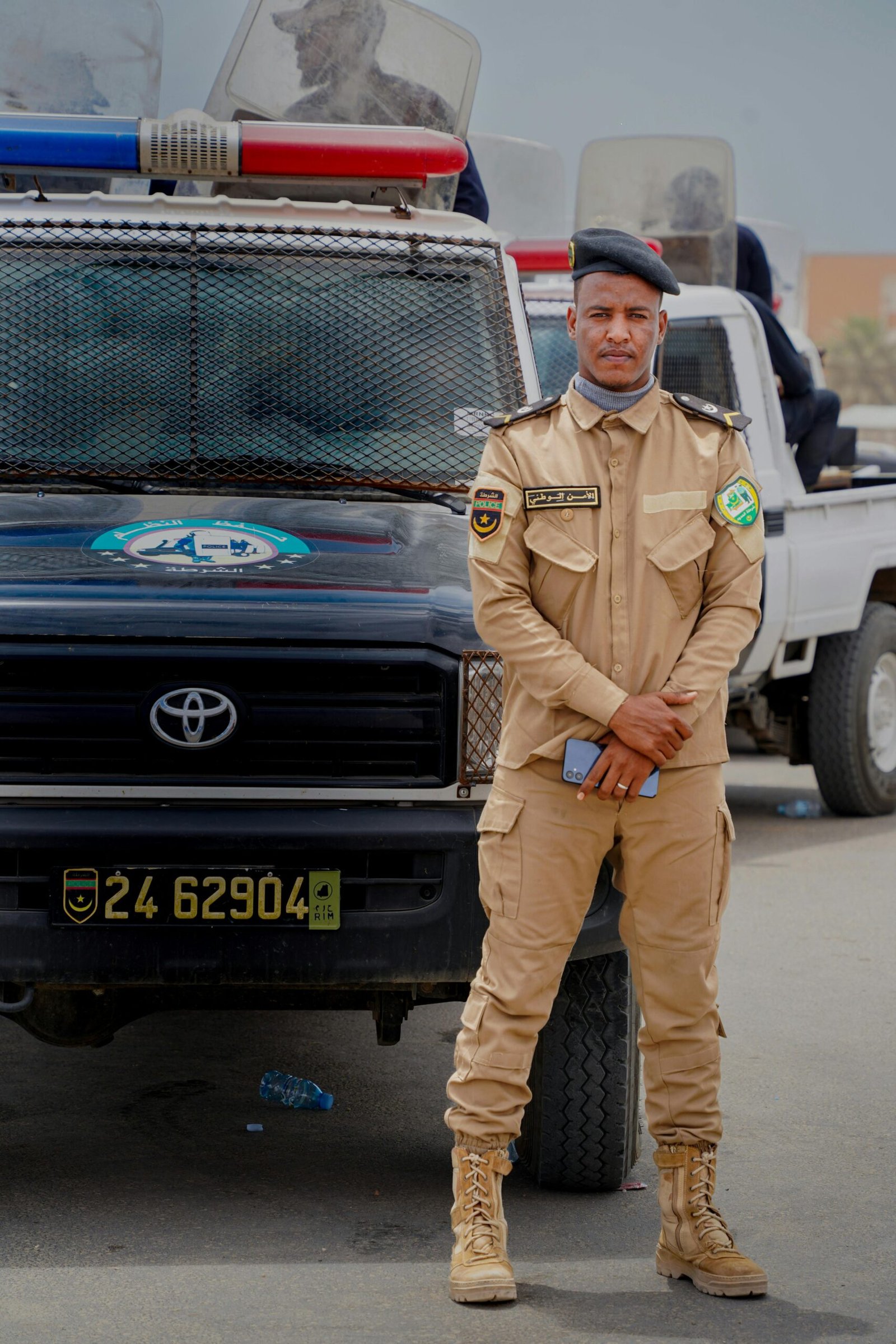 Secure Transport A security officer stands confidently in front of a patrol vehicle with a composed demeanor.
